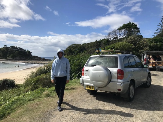 Teun at an Australian beach next to a car with a surfboard on the roof